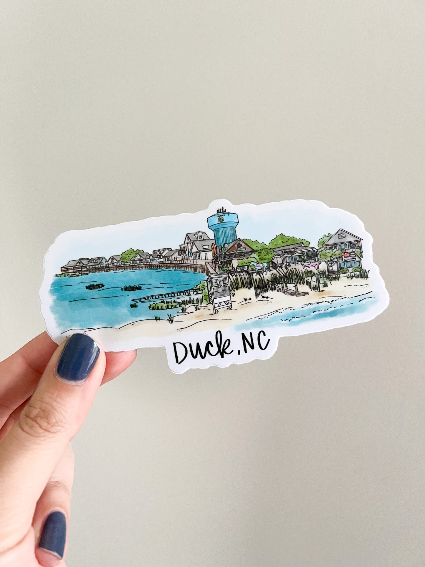 artistic skyline created of various landmarks and shoreline vistas found in Duck North Carolina. Sticker being held on white background.