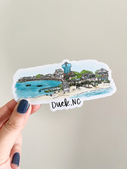 artistic skyline created of various landmarks and shoreline vistas found in Duck North Carolina. Sticker being held on white background.