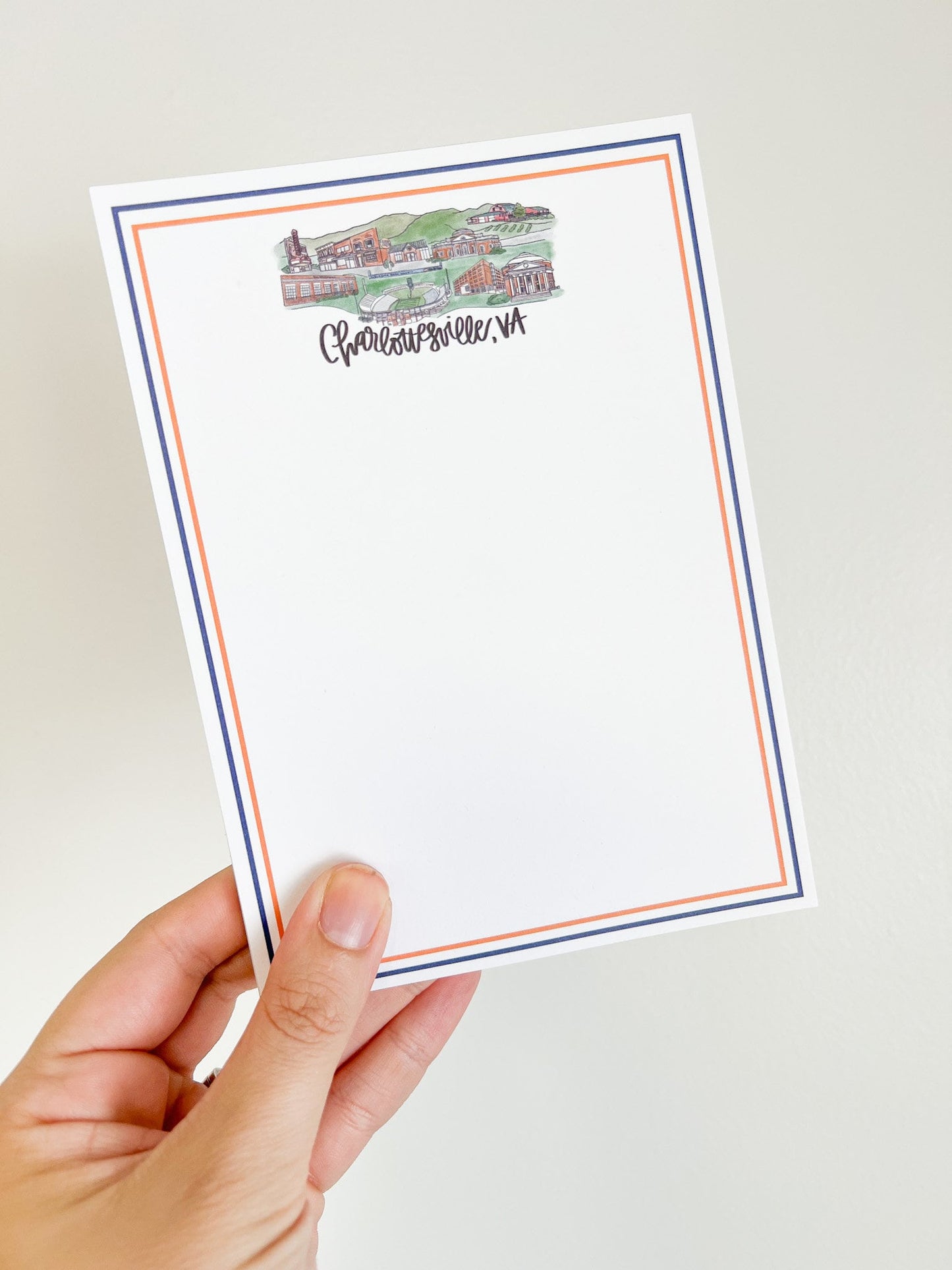 Notepad with navy and orange boarder. Charlottesville Virginia landmarks grouped together in a skyline design at the top with the words Charlottesville, VA below.